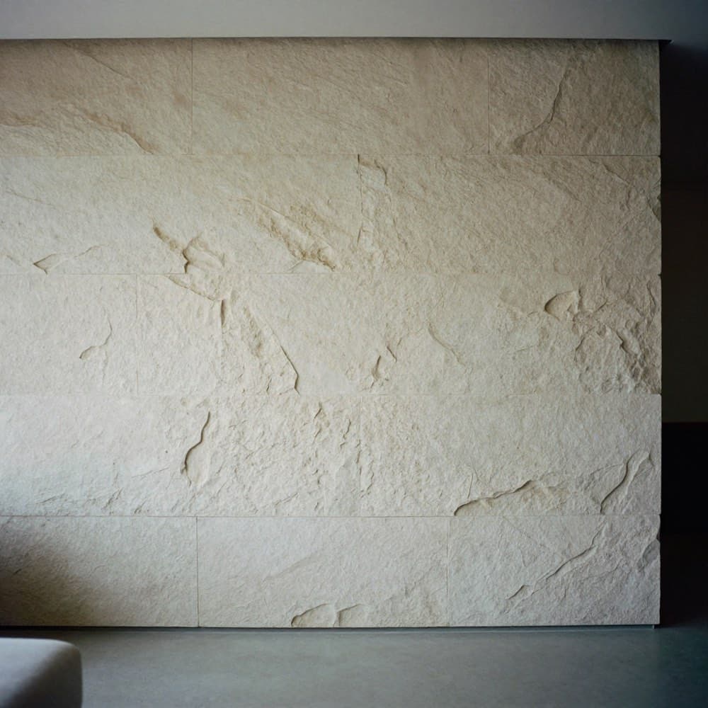 Wand aus hellen Steinpaneelen mit gebrochener Oberfläche